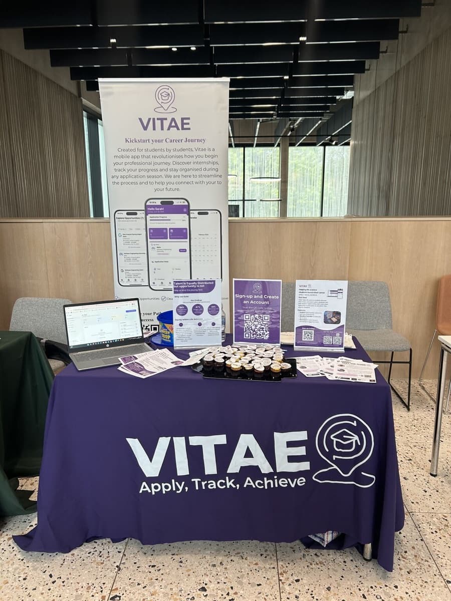 The Vitae stand at Warwick: a purple Vitae tablecloth, a laptop, cupcakes and a pull-up banner